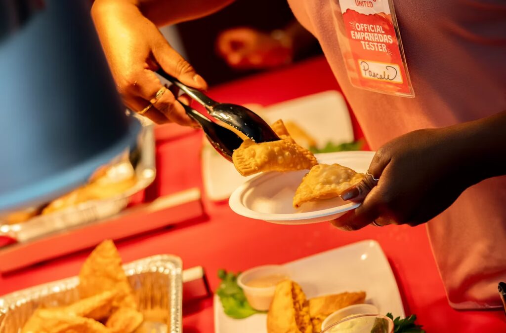 A woman placing empanadas from a serving tray onto a plate